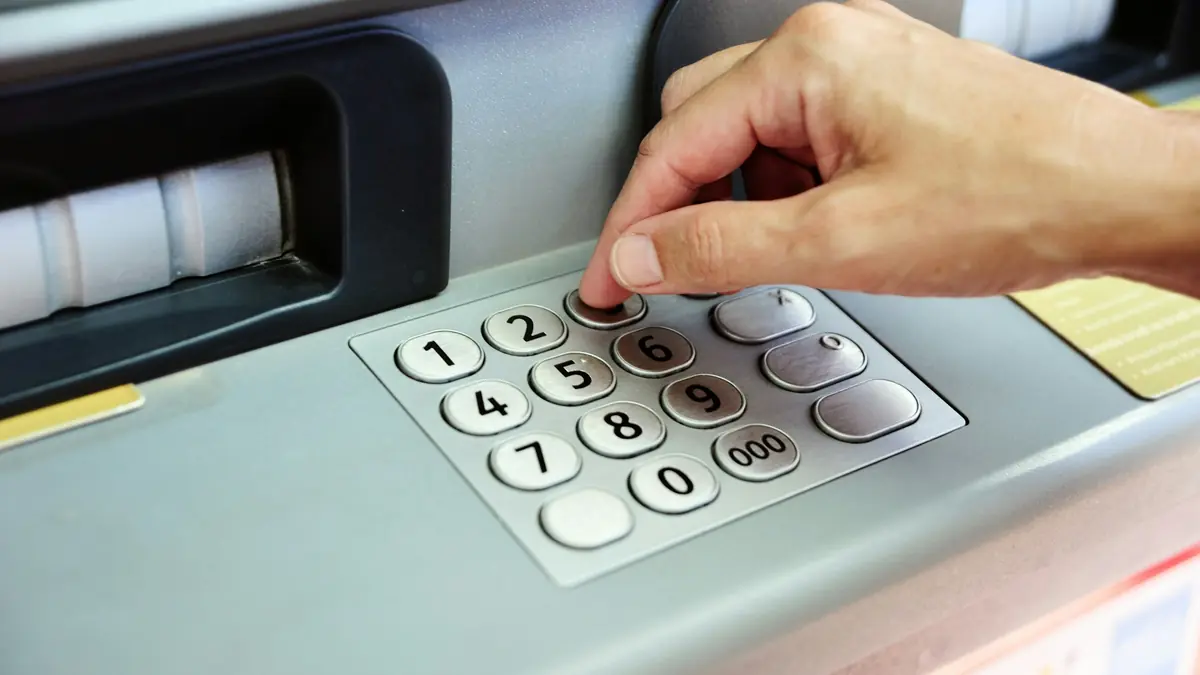 Nhập mã PIN trên bàn phím máy ATM sau khi rút tiền Kubet về tài khoản ngân hàng chính chủ